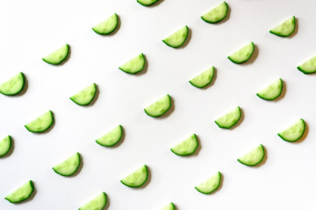 Motif répétitif de demi-cercles tranchés de concombres de légumes crus frais pour salade isolé sur blanc