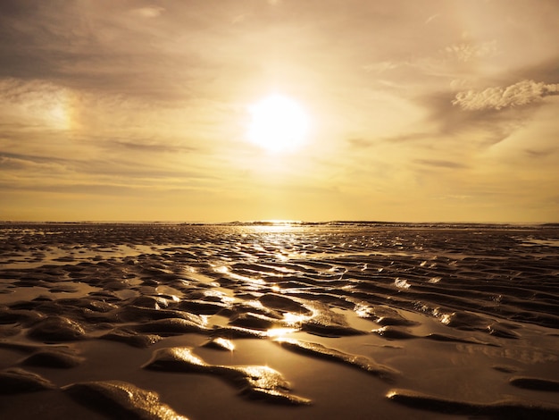 Motif de surface doré sable sur la plage de coucher du soleil.