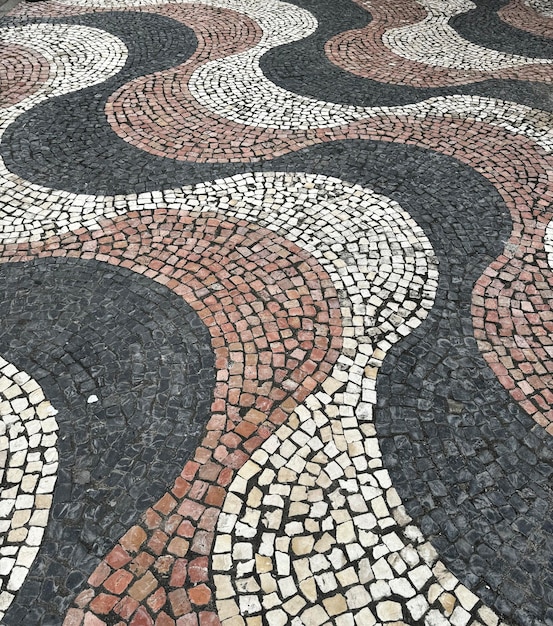 Des motifs ondulés en plein air de pavés noirs, rouges et blancs de texture sans couture installés dans le centre-ville