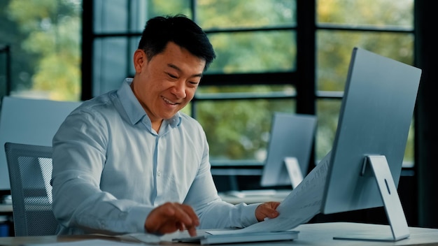 Émotionnel heureux homme asiatique homme d'affaires greffier spécialiste travailleur chinois coréen mâle faisant de la paperasse