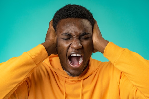 Émotionnel hurlant jeune homme africain debout isolé sur fond de menthe