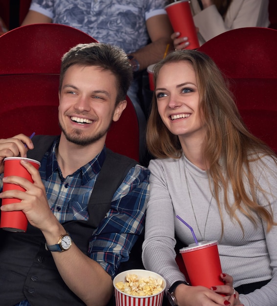 Émotionnellement heureux couple de jeune et belle petite amie aux cheveux longs et petit ami en chemise à carreaux en regardant un nouveau film de comédie au cinéma moderne