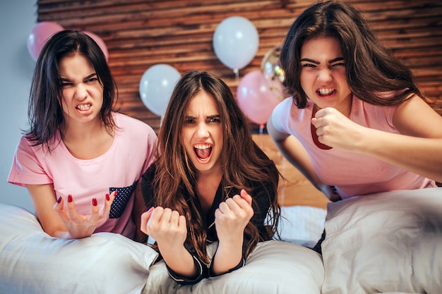 Émotionnelles jeunes femmes s'asseoir sur le lit avec des visages en colère. Les filles sont très émotives.