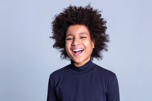 Émotions devant la caméra. Rire beau mec positif restant sur fond gris tout en participant à une séance photo sérieuse