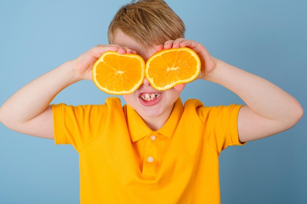 Émotions positives Garçon surpris avec de l'orange sur les yeux Enfant en t-shirt jaune