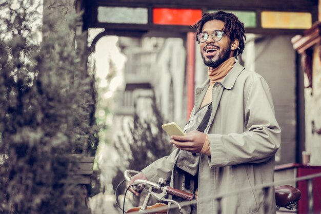 Émotions sincères. Bel homme gardant le sourire sur son visage tout en étant heureux de bonnes nouvelles