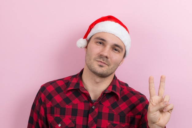 Émotions sur le visage, sourire, joie. Un homme dans un lapin à carreaux et un chapeau de Noël rouge