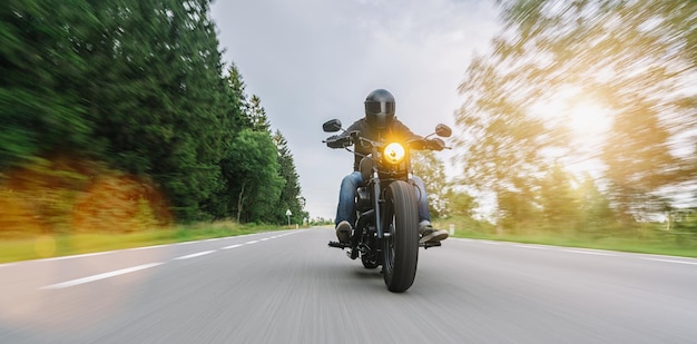 moto chopper sur la route forestière. s'amuser à conduire sur une route déserte lors d'un tour à moto. copyspace pour votre texte individuel.