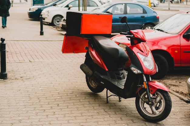 La moto de livraison de pizza rouge se tient dans la rue avec un sac ouvert Service Transport alimentaire Ville urbaine en plein air Garé et attendant la commande et la livraison au client