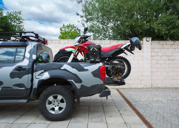 Moto de moto de saleté rouge à l'arrière du camion camouflage avec équipement de sécurité.