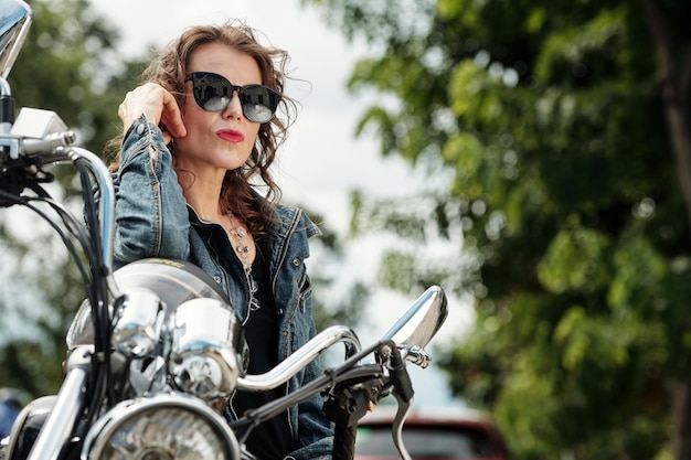 Motocycliste féminin prenant des lunettes de soleil