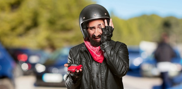 Photo motocycliste tenant un modèle de voiture rouge