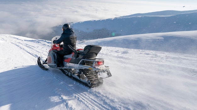 La motoneige se déplace sur la pente d'une montagne enneigée.