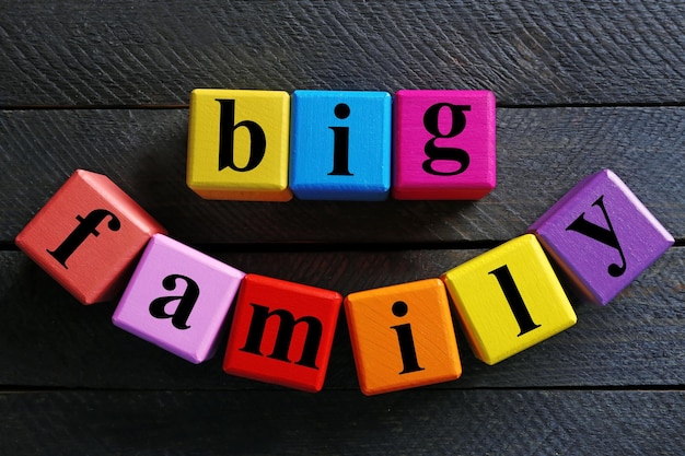 Des mots de couleur BIG FAMILY sur un fond en bois