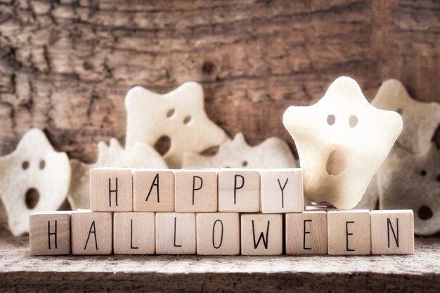 Mots Happy Halloween sur cubes en bois avec groupe de fantôme effrayant sur fond de bois automne