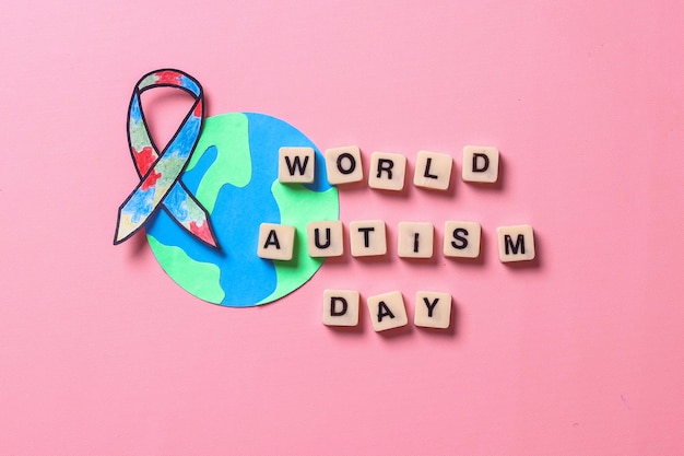 Mots de la Journée mondiale de l'autisme avec globe terrestre et ruban de sensibilisation à l'autisme. Journée mondiale de sensibilisation à l'autisme.