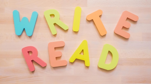 Mots LIRE et ÉCRIRE à partir de lettres en bois multicolores sur table en bois.