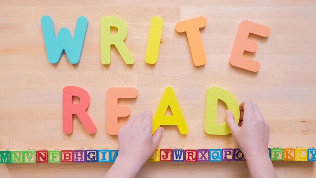 Mots LIRE et ÉCRIRE à partir de lettres en bois multicolores sur table en bois.