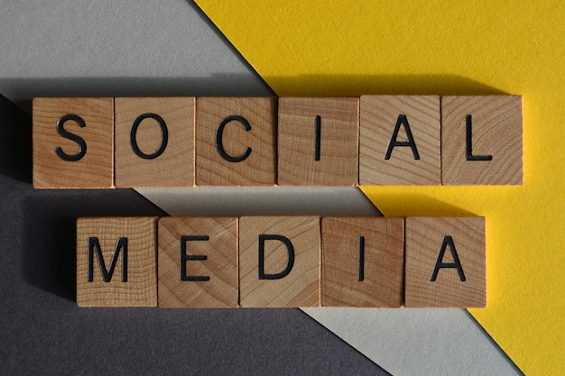 Des mots de médias sociaux en lettres d'alphabet en bois isolés sur un fond jaune et gris