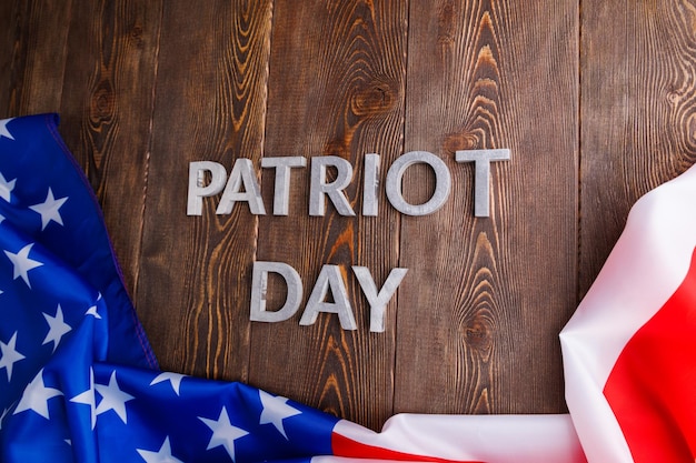 Mots patriot day posés avec des lettres d'argent sur la surface de la planche de bois avec le drapeau usa