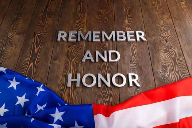 Les mots se souviennent et honorent posés avec des lettres en métal argenté sur fond de bois avec le drapeau américain en dessous