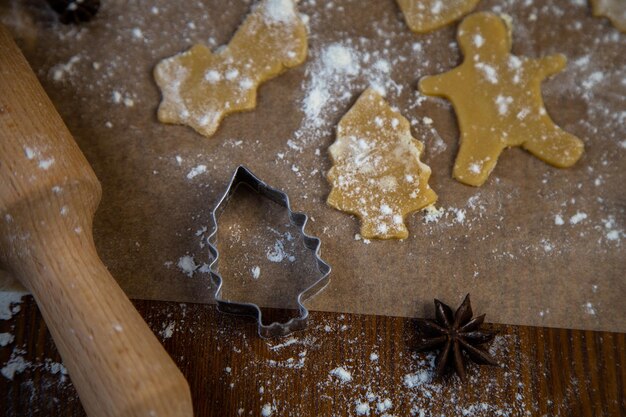 Le moule à biscuits en forme d'arbres de Noël sur parchemin posé à côté de lui est découpé dans le ...