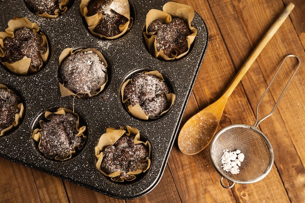 Moule de cuisson avec un savoureux muffins au chocolat sur la table en bois