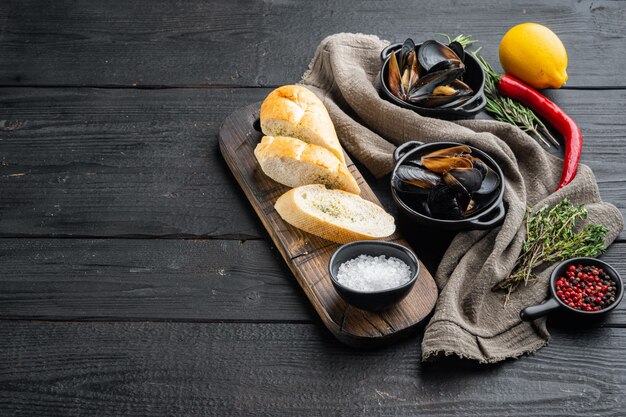 Moules au four avec des ingrédients sur fond de table en bois noir