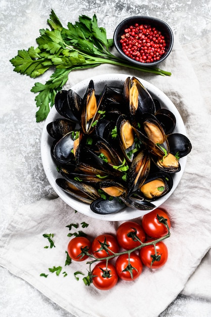 Moules aux herbes et sauce dans un bol. Fond gris. Vue de dessus