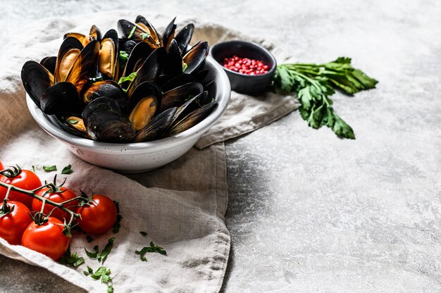 Moules aux herbes et sauce dans un bol. Gris surface