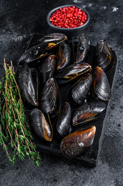 Moules bouillies en coquilles sur une planche de marbre. Fond noir. Vue de dessus.