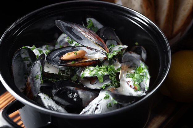 Moules bouillies avec une sauce dans une poêle noire