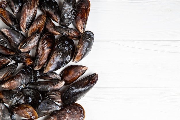 Moules crues fraîches sur fond de bois blanc