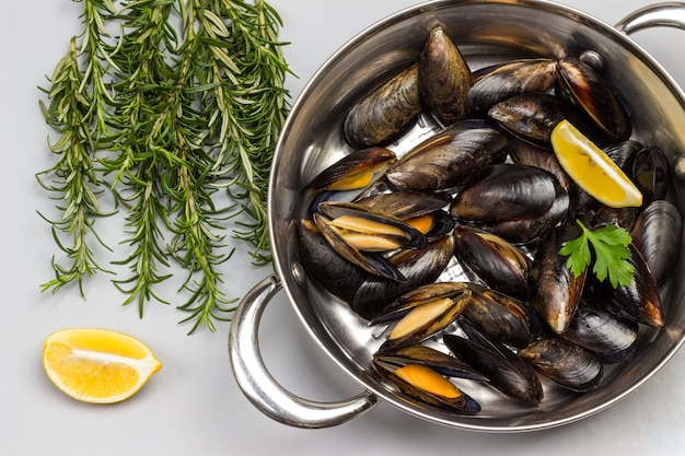 Moules de crustacés dans une poêle. Romarin et citron sur table. Fruits de mer crustacés