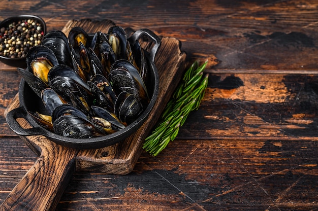 Moules cuites avec sauce au vin blanc dans une casserole aux herbes