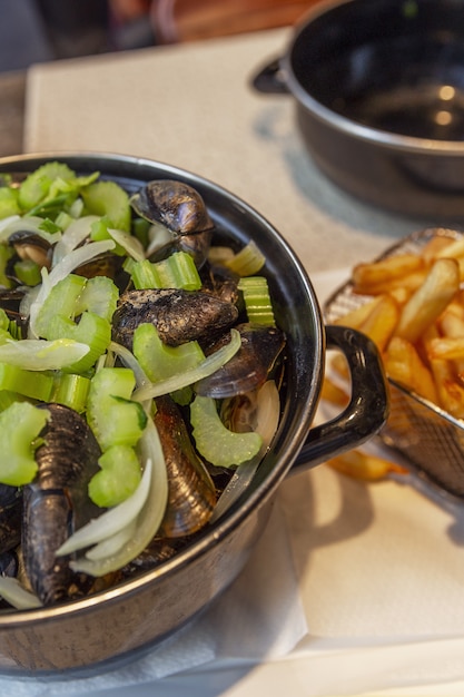 Moules dans une casserole et frites sur une table dans un café. Snack traditionnel belge.