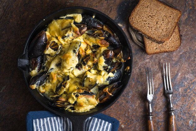 Moules dans une poêle avec sauce au fromage serviette en rayures bleues