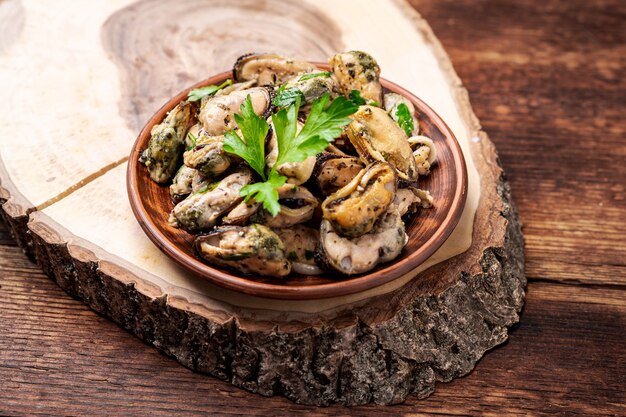 Moules décortiquées en sauce sur fond de bois foncé.