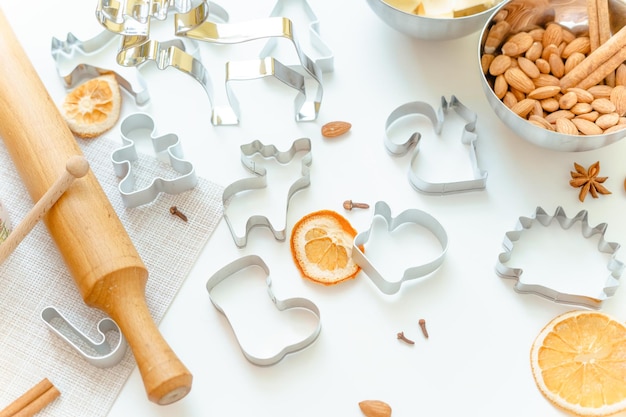 moules pour pain d'épice de Noël sous forme d'animaux sur une table blanche avec des amandes, des étoiles d'anis, d