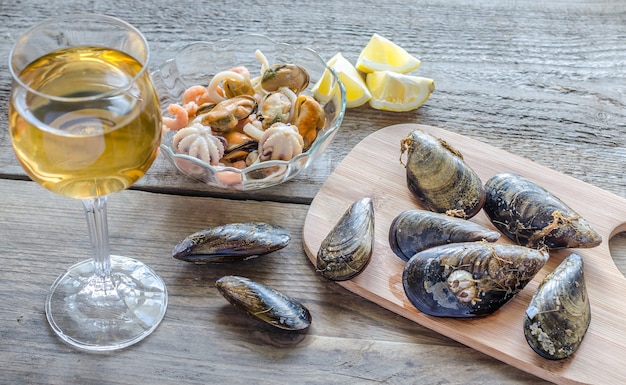 Moules avec un verre de vin blanc sur la table en bois