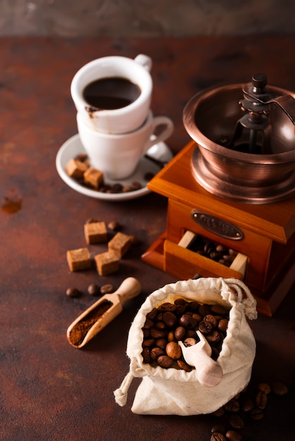 Moulin à café, tasse de café et sac de grains de café en arrière-plan.