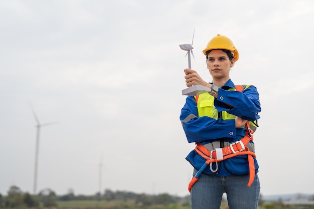 Moulin à vent ingénieur féminin en uniforme et casque de sécurité tenant le modèle d'éolienne