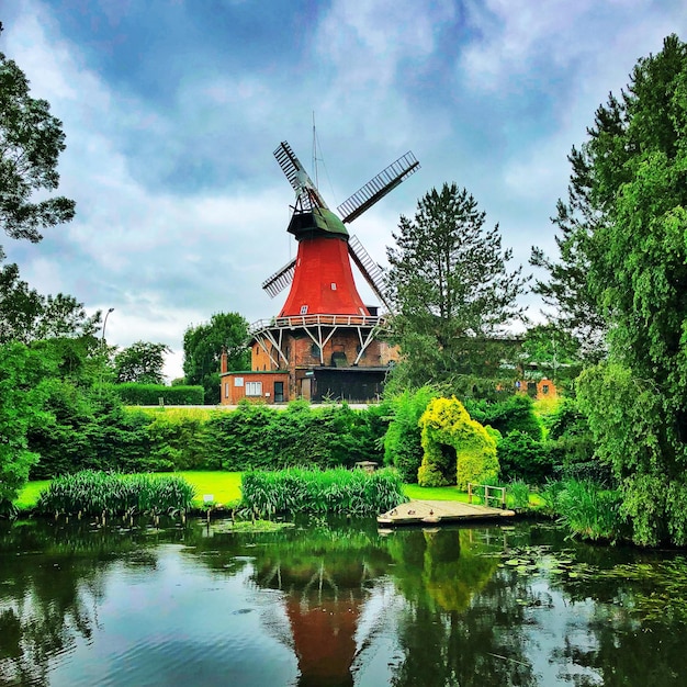 Moulin à vent traditionnel au bord d'un lac contre le ciel