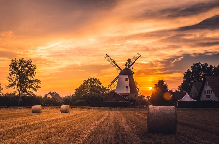Photo moulin à vent traditionnel sur un champ contre le ciel au coucher du soleil