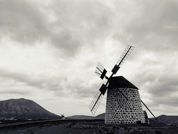 Photo moulin à vent traditionnel sur le paysage contre un ciel nuageux