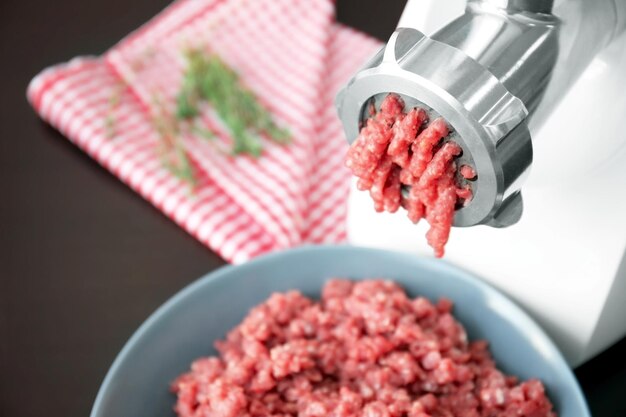 Photo un moulin à viande avec de la viande fraîche sur la table de la cuisine