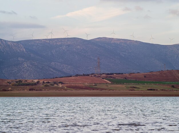 Moulins à vent dans les montagnes au-dessus du lac au coucher du soleil en Grèce