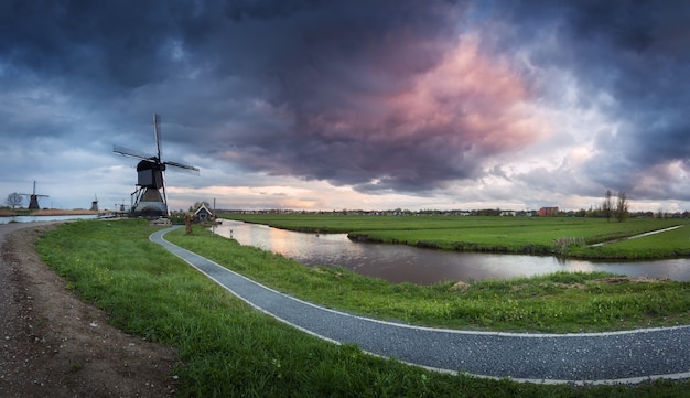 Moulins à vent hollandais traditionnels près de canaux d'eau avec ciel nuageux, paysage