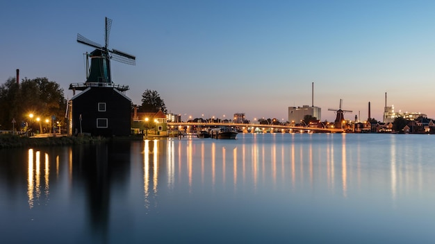 Photo des moulins à vent traditionnels au bord d'une rivière contre le ciel au coucher du soleil