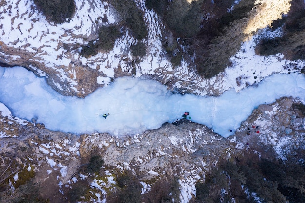 Photo mountaineer man est à la tête de l'escalade sur glace sur la cascade gelée vue aérienne topdown barskoon valley kirghizistan